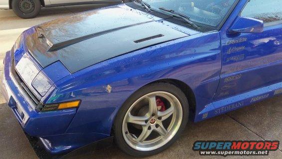 1989 Mitsubishi Starion front quarter view, blue paint, black hood scoop, aftermarket decals on side