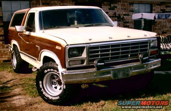 Ford Bronco with wood paneling, front end visible, parked outside a brick house