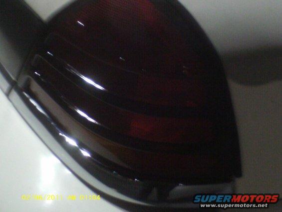 Close-up of a dark red vehicle taillight with chrome trim