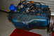1963 Ford Ranchero - A blue engine block with various components attached, including an oil filter and distributor, is shown in a workshop setting.
