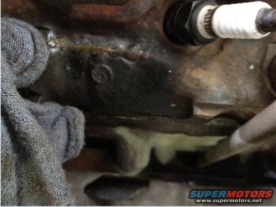 Close-up of an engine block with a spark plug and a gray rag