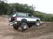 1994 Ford Bronco - 1994 Ford Bronco shown off-road, navigating a dirt incline with its spare tire mounted externally.