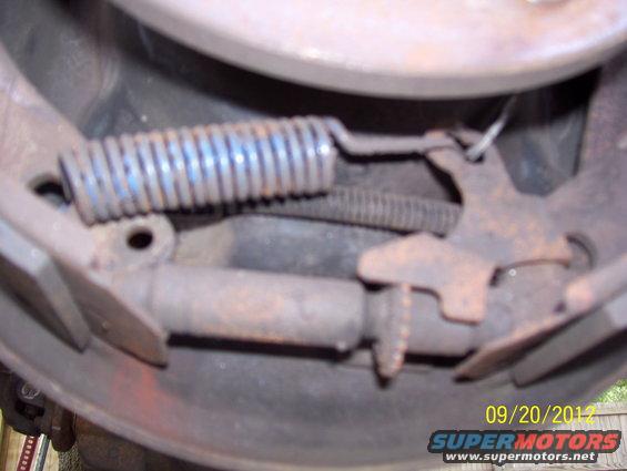 Close-up of a rusty brake drum assembly with a spring and linkage