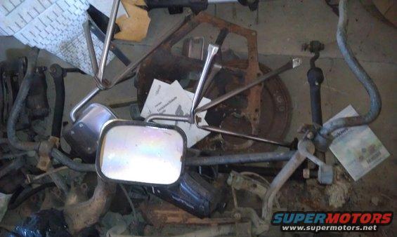 Pile of assorted car parts including a side mirror, brake rotor, and suspension components