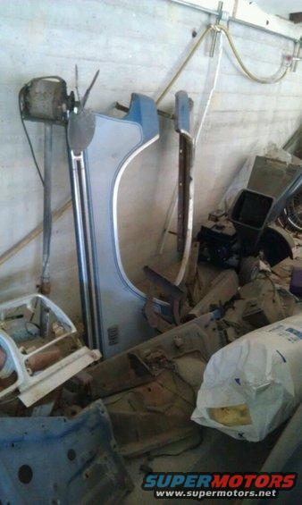 Car fender and other parts piled up in a storage area. Some parts are blue and silver