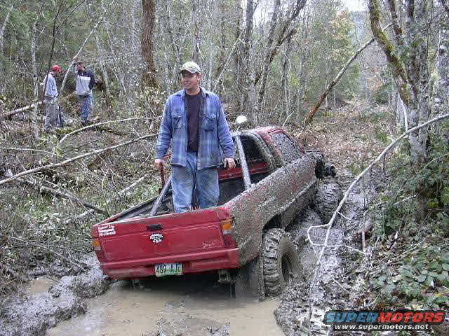 Red pickup truck stuck in mud, rear view. License plate 489 AJE