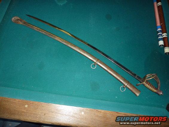 Antique sword with scabbard on a green felt surface