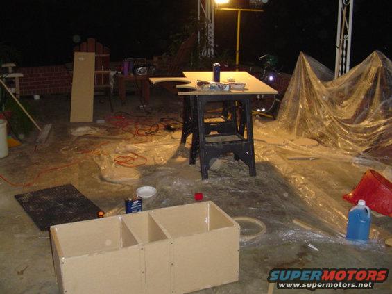 Unfinished wooden boxes and construction materials on a concrete floor at night