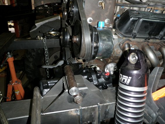 Close-up of engine pulleys, belts, and steering pump assembly with a "ORI STRUTS" shock absorber visible