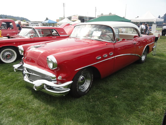 Red and white 1955 Buick with chrome trim and three portholes on fender