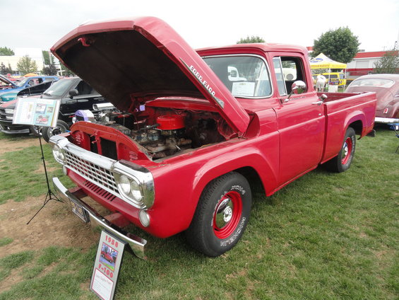 Red 1958 Ford F-100 pickup truck, hood open showing engine. Sign in front says 1958 F-100