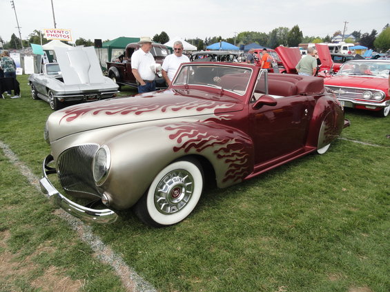 Maroon and silver convertible with flame paint, wide whitewall tires, and chrome grille
