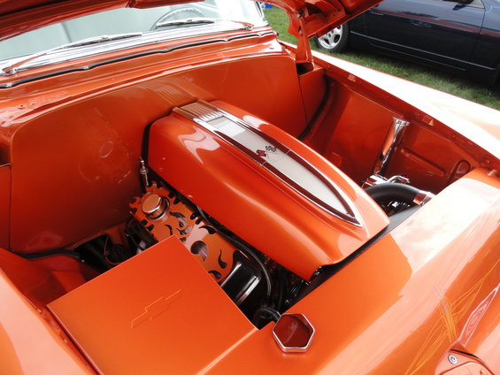 Orange engine bay with custom orange engine cover and flame-decorated engine parts. Chevrolet logo visible on a panel