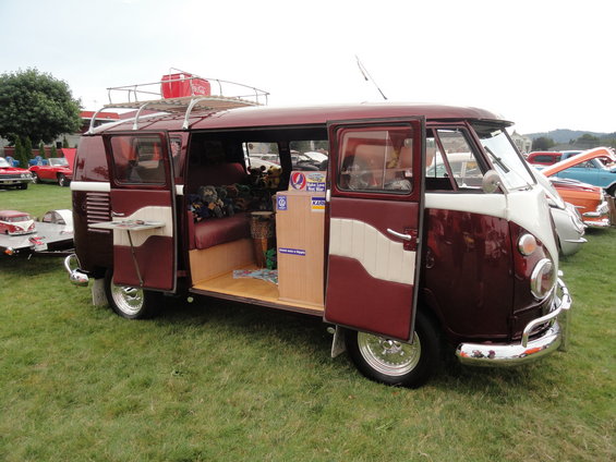 Maroon and white 1967 Volkswagen Type 2 bus with open doors, camping interior, and roof rack