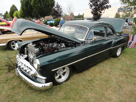 Dark green 1953 Chevrolet sedan with hood open, chrome grille, and custom wheels