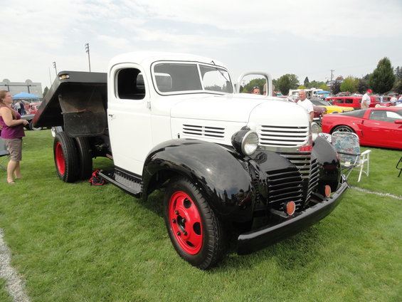 White flatbed truck with black fenders and red wheels parked on grass