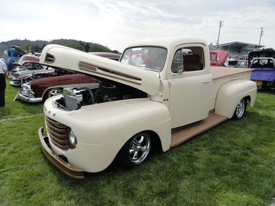 Cream-colored pickup truck, hood open, showing engine. Other cars in background