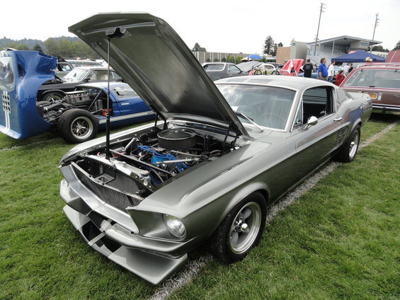 Gray 1967 Ford Mustang Fastback with hood open, showing engine. Custom front splitter with black and white stripes