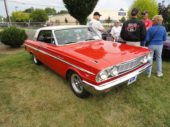 Red 1964 Ford Fairlane with a white roof parked on grass