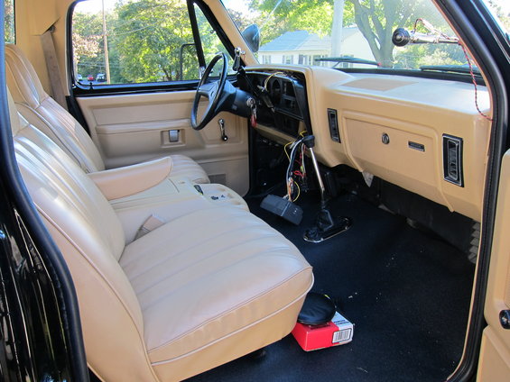 Tan interior of a pickup truck, showing seats, dashboard, and steering wheel. Wires are exposed near the center console