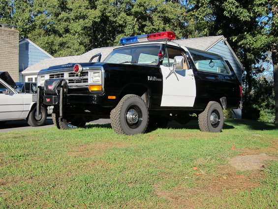 Black and white police SUV with light bar, push bumper, and "Ram" badging