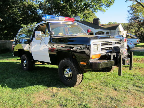 1987 Dodge Ramcharger police SUV with light bar and push bumper parked on grass