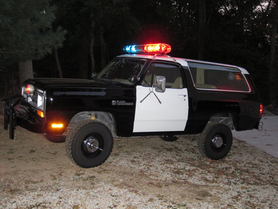 1987 Dodge Ramcharger police SUV with light bar on roof, parked outdoors at night