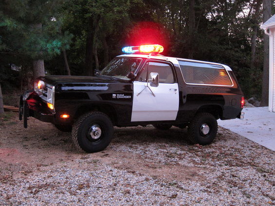 Black and white police SUV with light bar, Ramcharger badging visible