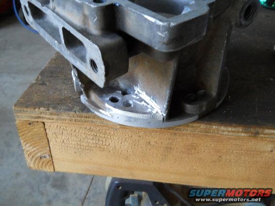 Metal engine part on wooden surface with SuperMotors logo