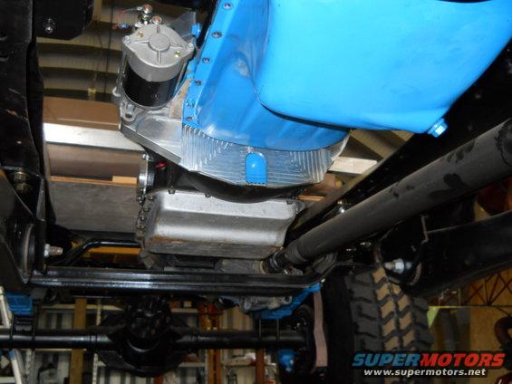 Underside view of vehicle engine with blue component and starter motor. Supermotors.net logo visible