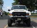 2001 Ford Excursion - A white 2001 Ford Excursion is parked outdoors, showing its front grille, bumper, and large tires.