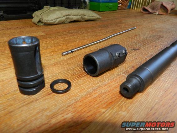 Gun barrel, muzzle brake, gas block, and rod on a wooden table