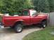 1996 Ford F-150 - This red 1996 Ford F-150 pickup truck is shown from the side, a lifted suspension and aftermarket wheels.