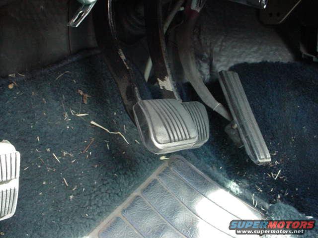 Car pedals and dark blue carpet with debris