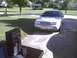 2003 Ford Crown Victoria - A silver sedan is parked in a driveway with a box of oil and cleaner on a table nearby.