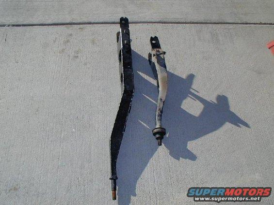 Two suspension control arms on concrete, one black, one silver