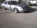 2003 Ford Crown Victoria - A silver 2003 Ford Crown Victoria sedan is parked outside, with a Chevrolet truck visible in the background.