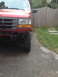 1996 Ford F-150 - Front corner view of a red 1996 Ford F-150, showing off its large tires and modified suspension.