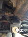 1996 Ford F-150 - Underside view of rusty suspension parts, including a coil spring and bolted bracket.