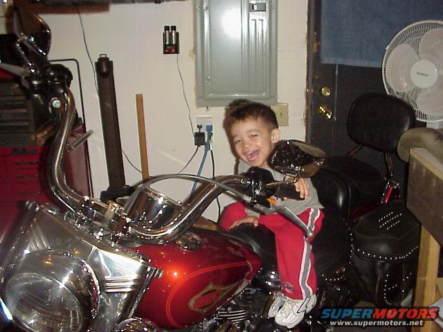 kid sitting on a red motorcycle in a garage