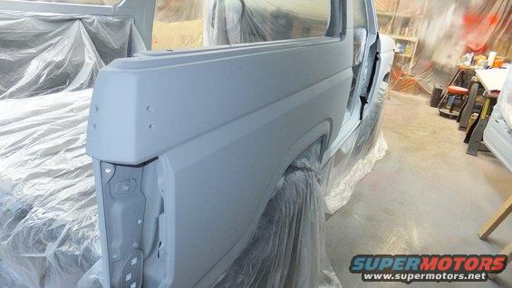 Bronco body covered in primer, doors open, in a spray booth