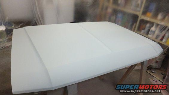 White car hood on sawhorses in a workshop