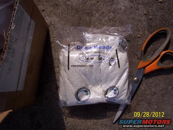Bag of Dyna Beads tire balancing beads next to orange-handled scissors and a cardboard box