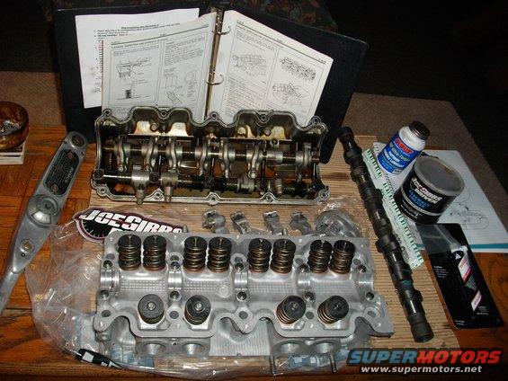 Engine cylinder head, camshaft, and assembly manual on a table