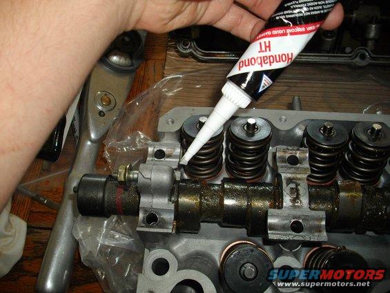 Applying Hondabond HT gasket sealant to an engine cylinder head with springs and camshaft
