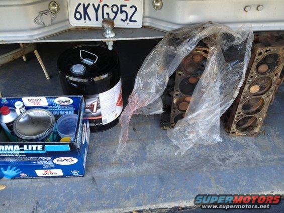 Truck bed with license plate 6KYG952, black drum, box of supplies, and engine parts