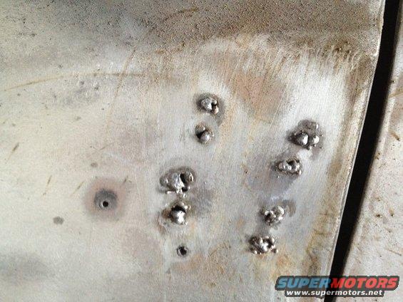 Close-up of several small, rough welding spots on a dull metal surface
