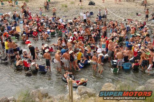 Crowd of people in a river with chairs and coolers