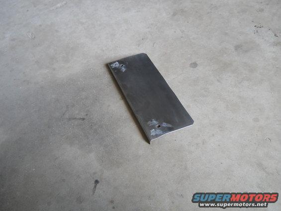 Flat metal plate with two holes, lying on a concrete floor