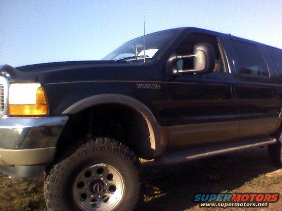 Black Ford Excursion with tan lower body panels, parked outside